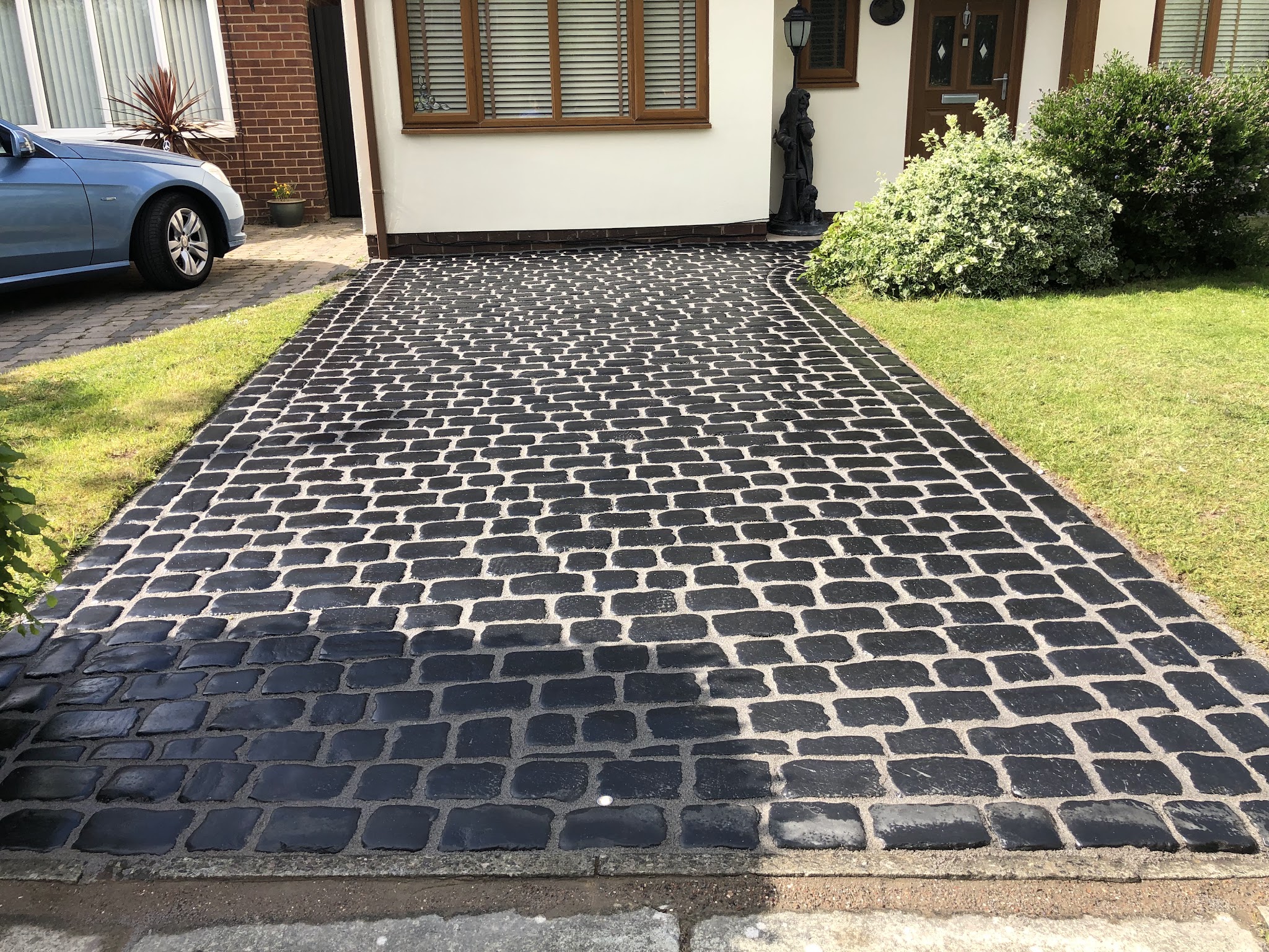 A black cobble-effect driveway in front of a house