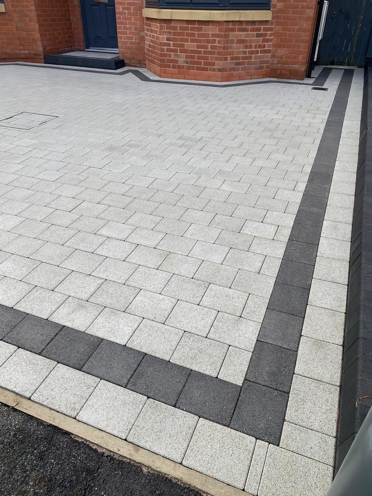 Silver block paving with a charcoal border in front of a new brick house